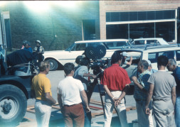 Director Gordon Parks looking through a camera with production crew around him in downtown Fort Scott, Kansas.