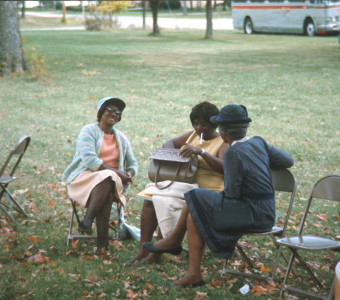 Three African American actresses, including Estelle Evans (Sarah Winger), in dark dress, seated together.